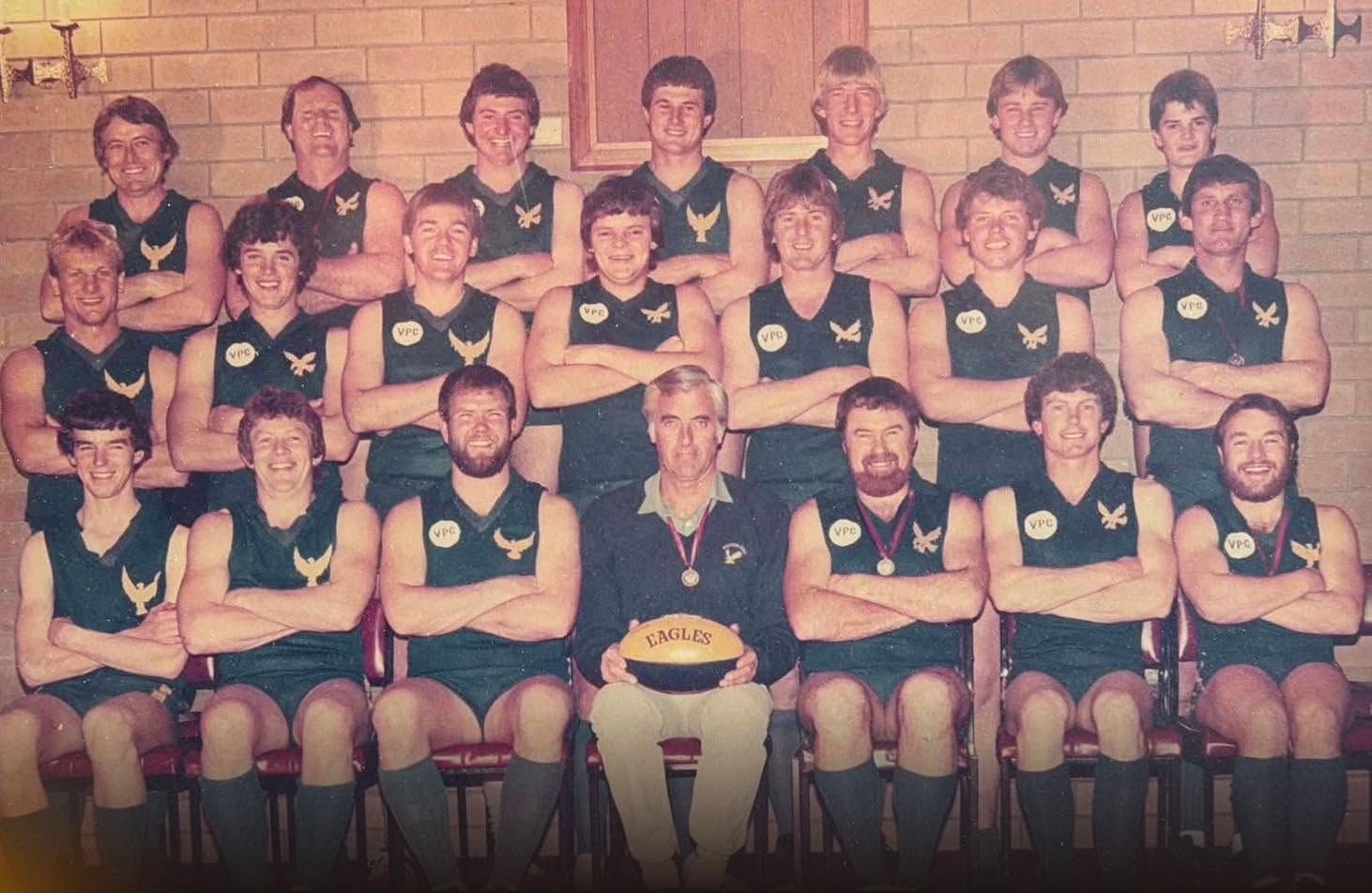 Hatherleigh's 1986 Reserves premiership team, three rows with the coach seated centre holding an Eagles football