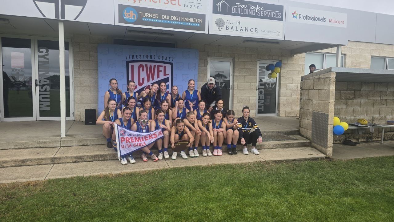The 2024 U16 Girls premiership team with their coaches, pennant, cup and shield