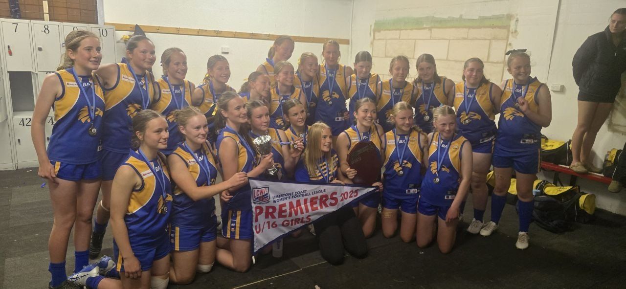 Hatherleigh U16 Girls celebrate in the rooms with the 2025 premiership pennant, cup and shield